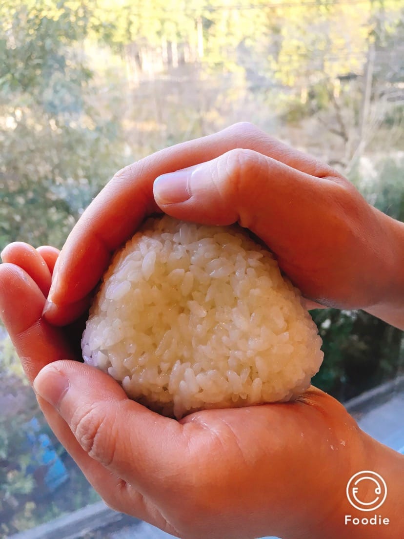 両手でおにぎりを握るようす（おにぎりと味噌汁作り体験）