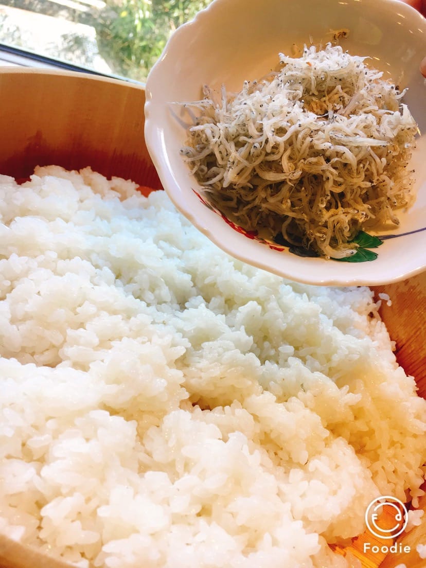 曲げわっぱのすし飯にしらすを加えるようす
