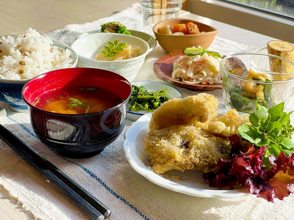 揚げ物、雑穀ごはん、味噌汁、季節の小鉢が並ぶ食事の一例